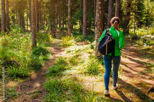 Woman tourist hiker walking through forest in Carpathian mountains enjoying view. Traveling in summer Ukraine. © maryviolet