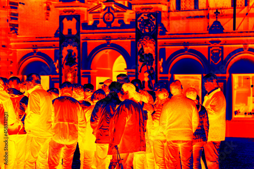 A crowd of men at the entrance to the pub, Scanning the people's body temperature with a thermal imager photo