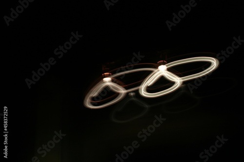 Ilustraciòn de luz blanca suspendida en el espacio formando figura abstracta con reflejos sobre fondo negro. photo