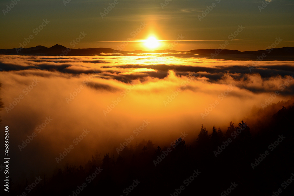 sunrise or sunset with clouds below, mountain range and orange trees