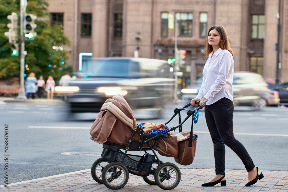 Woman with child in baby carriage walks during maternity leave. Woman with child in baby carriage walks during maternity leave.