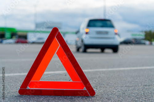 Warning triangle. A car with a flashing emergency light in the parking accident.