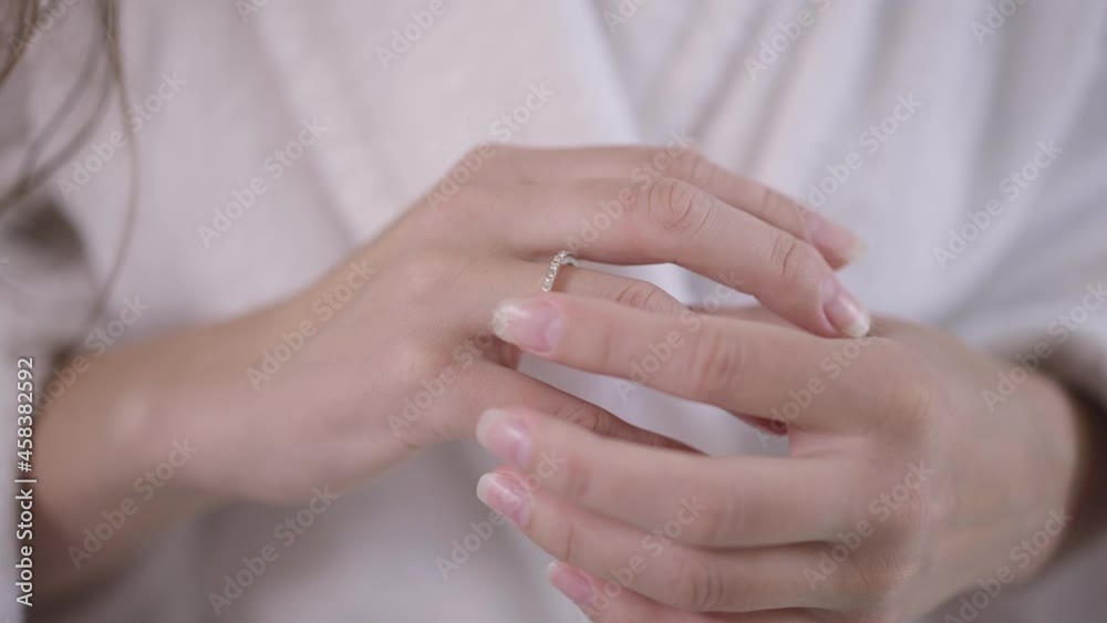 Close-up slim female Caucasian young hands touching engagement ring on finger. Unrecognizable happy engaged woman in white bathrobe indoors at home. Happiness and marriage concept Close-up slim female Caucasian young hands touching engagement ring on finger. Unrecognizable happy engaged woman in white bathrobe indoors at home. Happiness and marriage concept