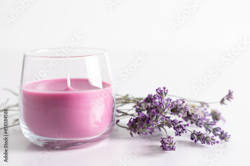 Aroma candles with colorful wax in glass with sprig of dry lavender on white background.