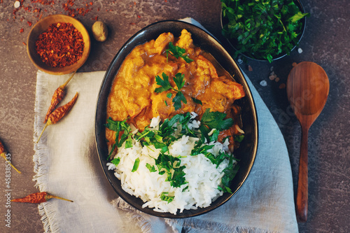 Traditional indian butter chicken in a bowl with basmati rice, spices and herbs