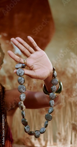 A vertical photo of an African hand which is holding a traditional necklace