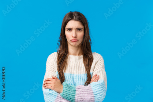 No one ever listens to what I want. Sulking offended gloomy, upset girlfriend feeling sad and displeased, pouting frowning and looking mad camera, cross hands over chest defensive, blue background photo