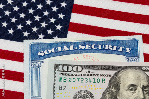 Social security card, 100 dollar bill and American flag. Concept of social security benefits payment, retirement and federal government benefits