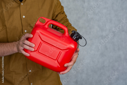 Man holds a red plastic gas canister in his hands. photo