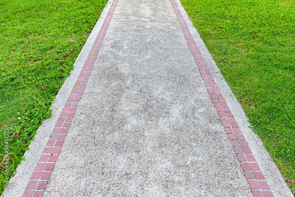 Long concrete walkway in the summer green garden