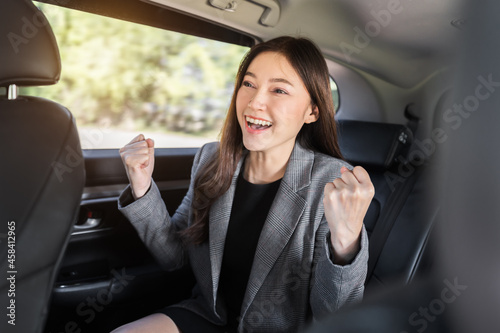 cheerful successed business woman sitting at the back seat of car © geargodz