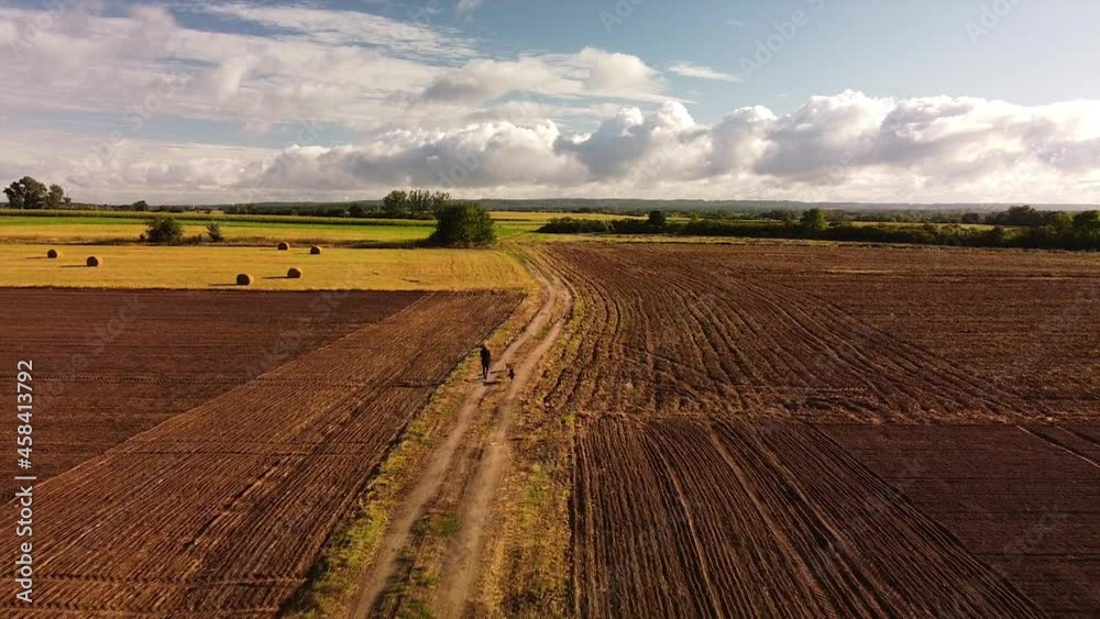 Flying backward and over a person walking two dogs on a dirt road. Flying backward and over a person walking two dogs on a dirt road.
