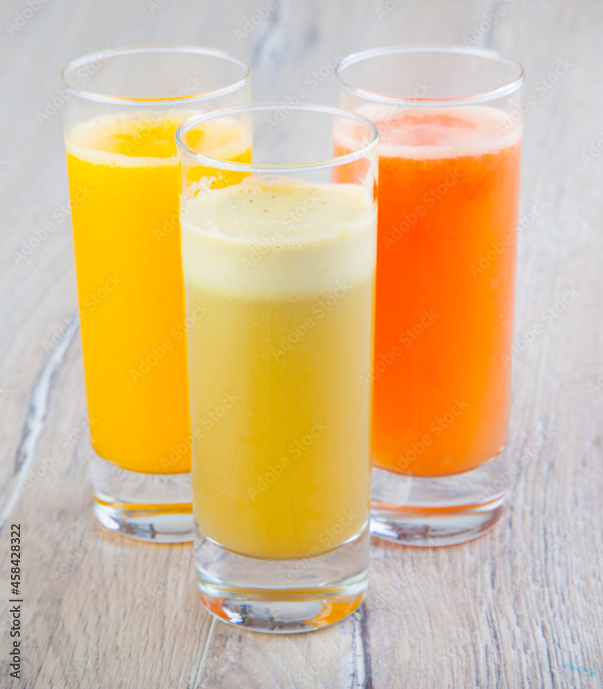 natural vegetable and fruit juices in a transparent glass on a wooden background