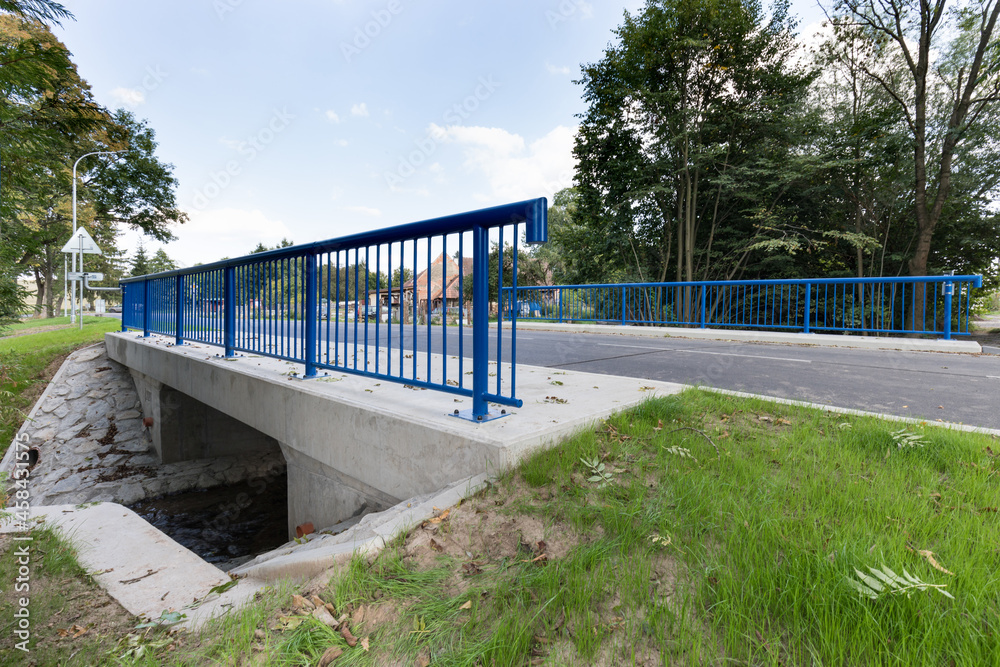 A new bridge across a small river. Summer time. 
Small reinforced concrete bridge after reconstruction. New asphalt.