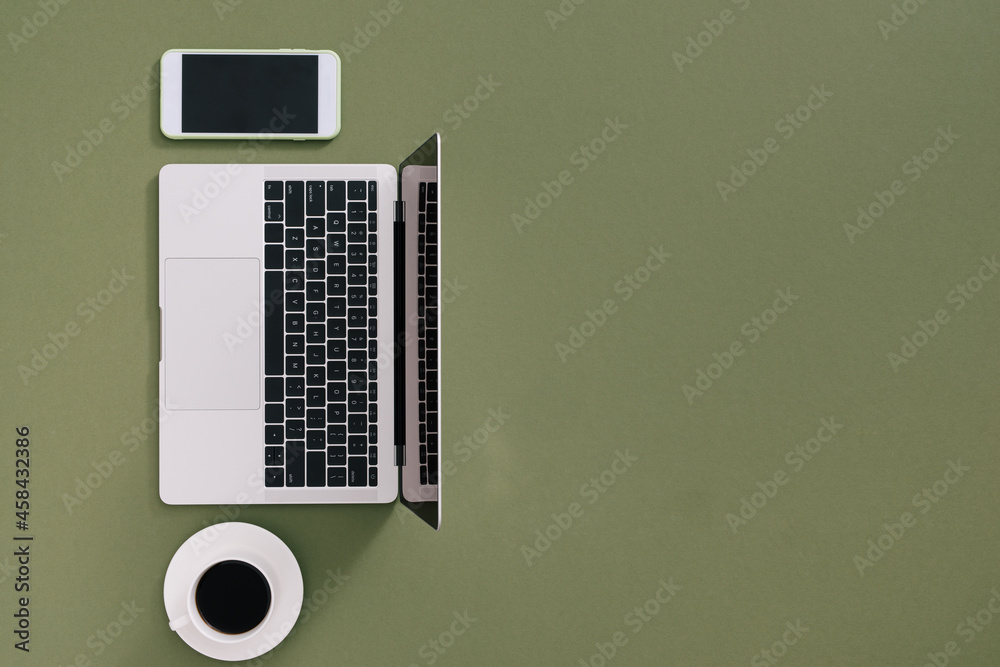 Minimalist flat lay composition of laptop, cell phone gadget, cup of coffee on table background. Workspace top view, copy space