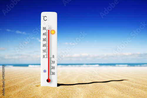 Hot summer day. Celsius scale thermometer in the sand. Ambient temperature plus 50 degrees