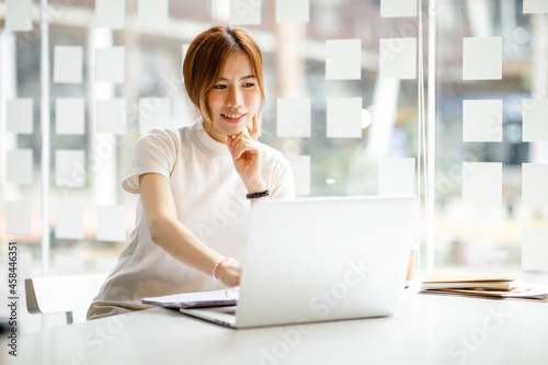 A young woman or businesswoman working on laptop computer in modern office. doing finances, accounting analysis, report data pointing graph Freelance education and technology concept.
