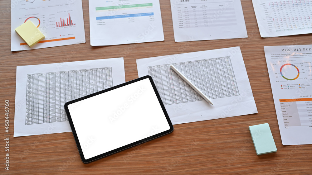Above view digital tablet and financial documents on wooden table.