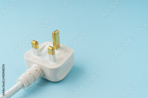 Three pin plug on light blue background with a copy space. photo