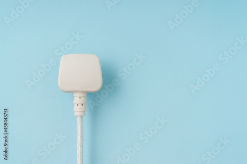Three pin plug on light blue background with a copy space.