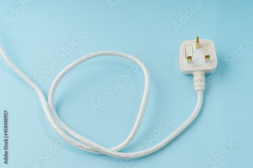 Three pin plug on light blue background with a copy space.