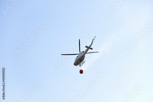 Fototapeta Naklejka Na Ścianę i Meble -  Firefighting helicopter transporting water to extinguish a fire. Hazard concept