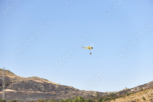 Firefighting helicopter transporting water to extinguish a fire. Hazard concept