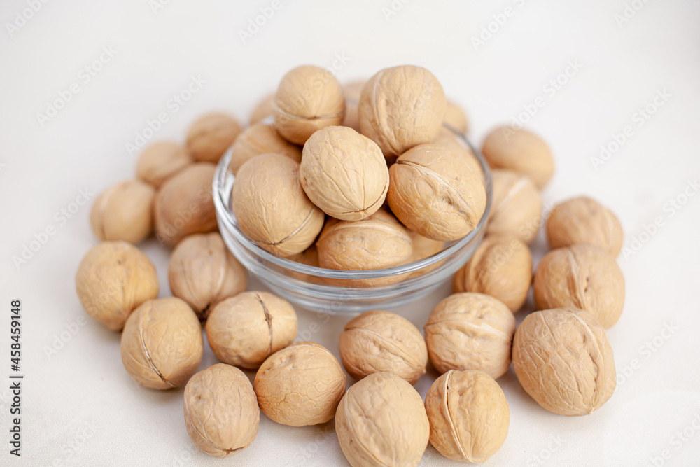 A lot of whole walnuts in a cup on a white background close-up. Healthy, organic food with a high content of protein and protein. A lot of whole walnuts in a cup on a white background close-up. Healthy, organic food with a high content of protein and protein.