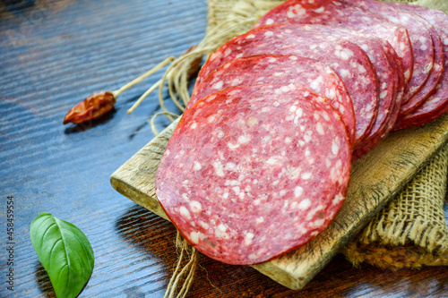 Photography Italian  dried thinly sliced   artisan  pork salami Milano , parmesan cheese, grissini , tomatoes   and fresh basil on wooden background