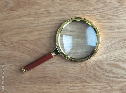 Magnifying glass on wooden desk as symbol of research and study.