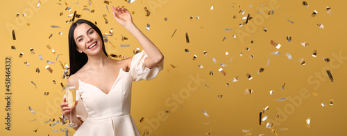 Canvas Beautiful woman with glass of champagne and falling confetti on color background