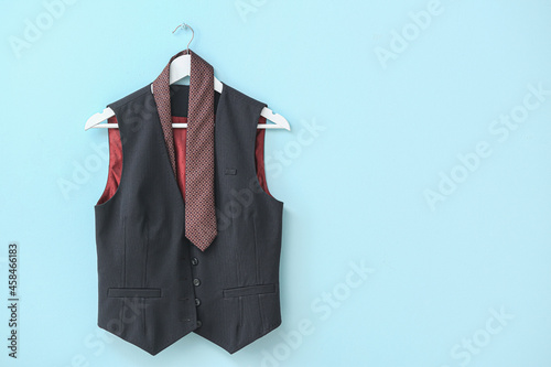 Hanger with necktie and vest hanging on color wall