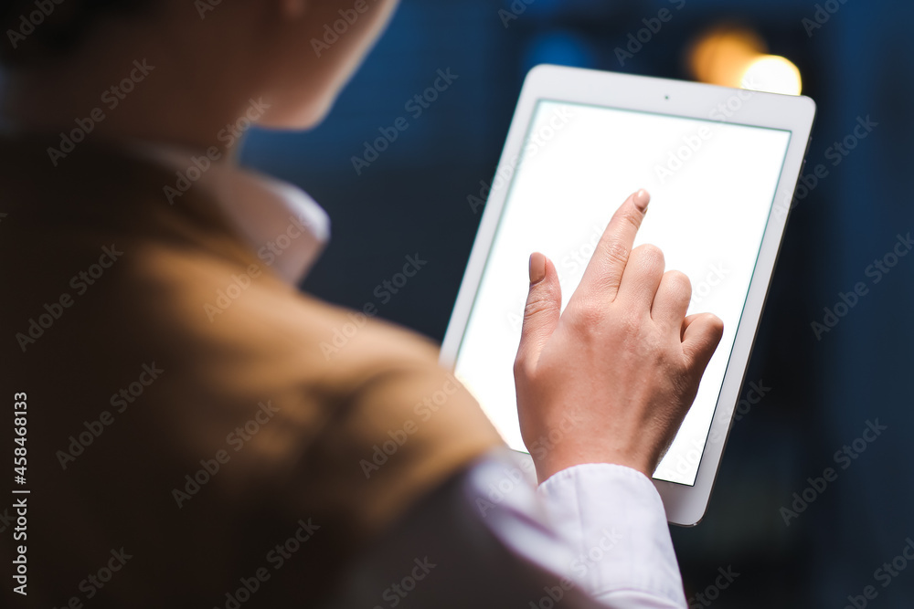 Young woman with tablet computer working in office at night