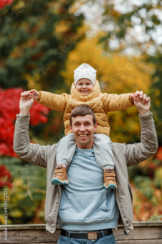 Happy dad and little daughter in the autumn park. Bright autumn colors.