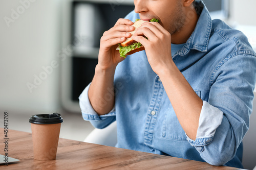 Young man eating tasty sand...