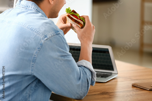 Young man eating tasty sand...