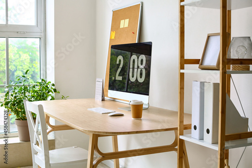 Modern home office workspace with computer monitor, wooden desk, and green pl...
