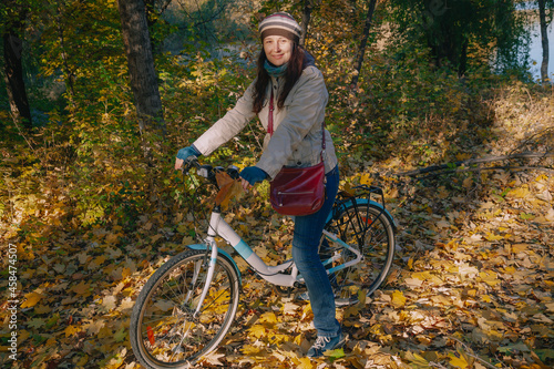 Pretty brunette sitting on bicycle in autumn park