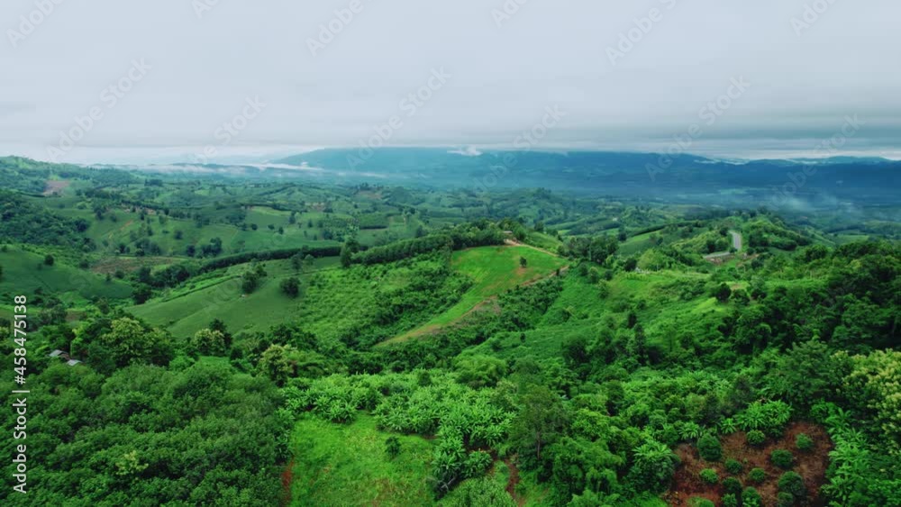 Aerial view drone shot of flowing fog waves on mountain tropical rainforest In the evening, Bird eye view image over the clouds Amazing nature background with clouds and mountain peaks.