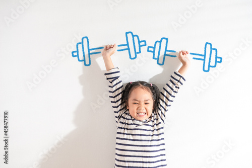 Murais de parede Funny Positive strong Asian little toddler kid girl lifting weight against the textured white background