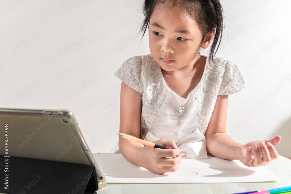 Asian adorable little kid toddler girl using a tablet mobile to online e-learning class learning from home while school closed during lockdown from coronavirus outbreak. The Home study child concept Asian adorable little kid toddler girl using a tablet mobile to online e-learning class learning from home while school closed during lockdown from coronavirus outbreak. The Home study child concept