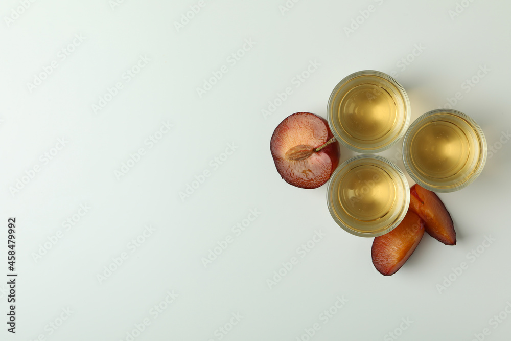 Plum vodka shots and ingredients on white background