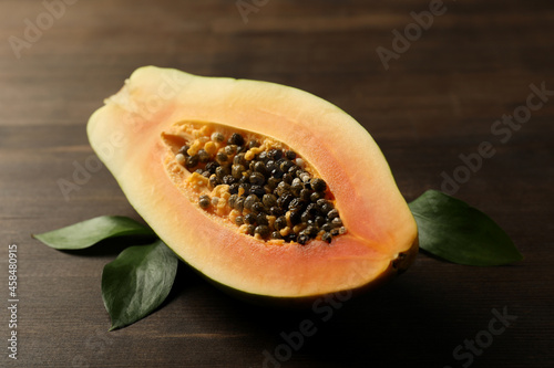 Half of papaya with leaves on wooden background
