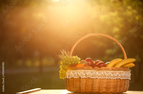 Wicker basket with fresh fruits on table outdoors
