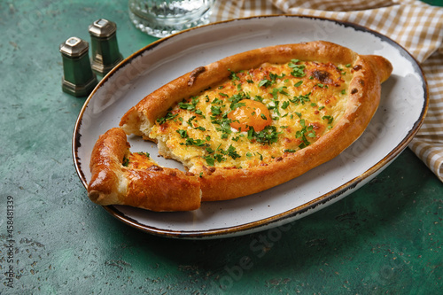 Plate with tasty Ajarian khachapuri on color background