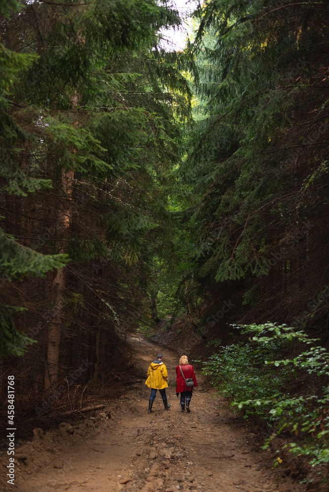 Middle age couple in raincoats walking through forest Middle age couple in raincoats walking through forest