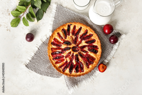 Fotografía Tasty plum pie and jug of milk on light background
