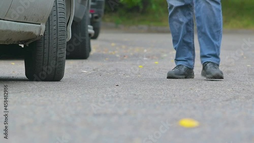A man gets into a car in windy autumn weather during the rain. The gait of a man walking to his car