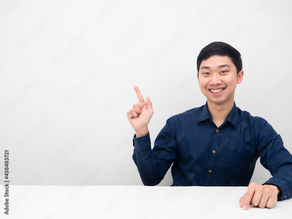 Cheerful man happy smile sitting and point finger at copy sapce white background Cheerful man happy smile sitting and point finger at copy sapce white background