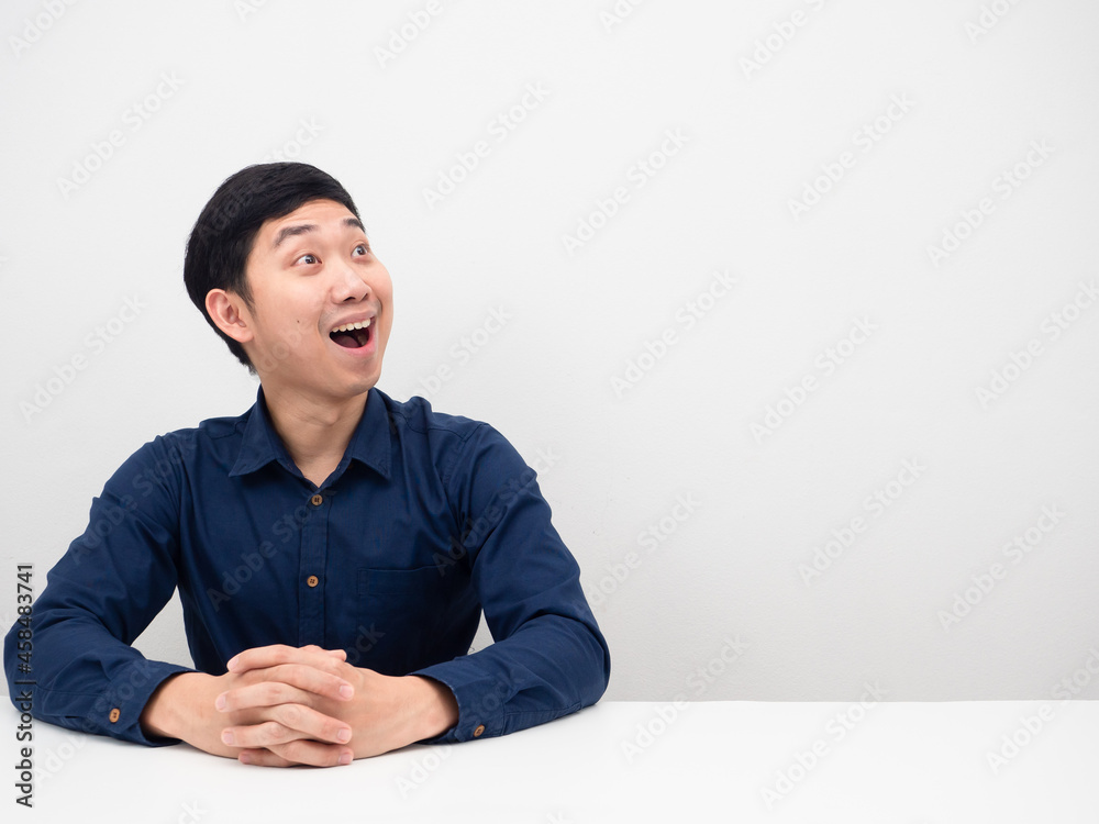 Young man sitting and feeling excited looking at copy space white background Young man sitting and feeling excited looking at copy space white background